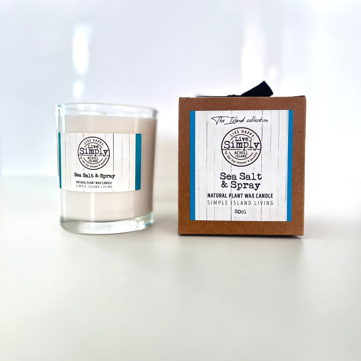 Glass candle labeled 'Sea Salt & Spray' next to its packaging on a white background