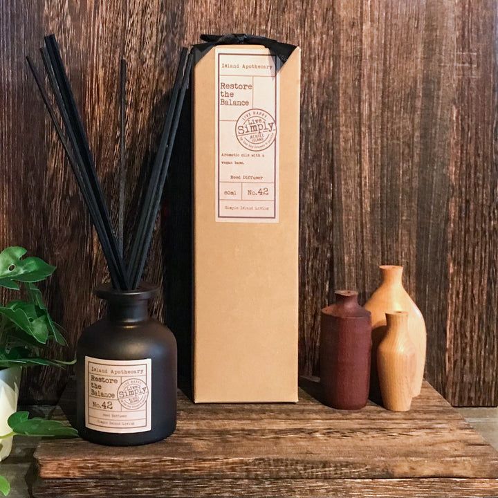 Diffuser with black sticks and decorative bottles on a wooden surface