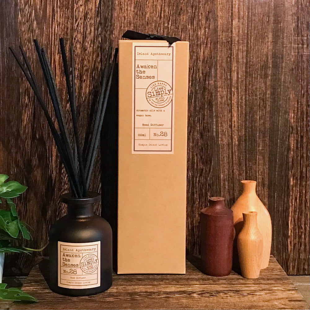 Aromatherapy diffuser with packaging and decorative vases on a wooden surface.